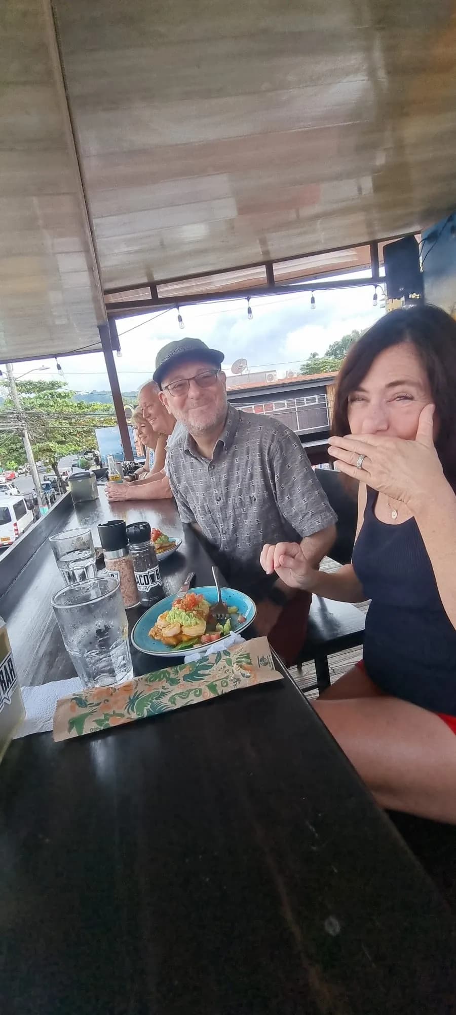 A couple laughing together at a restaurant table with a colorful dish in front of them on the Taste of Jaco food tour