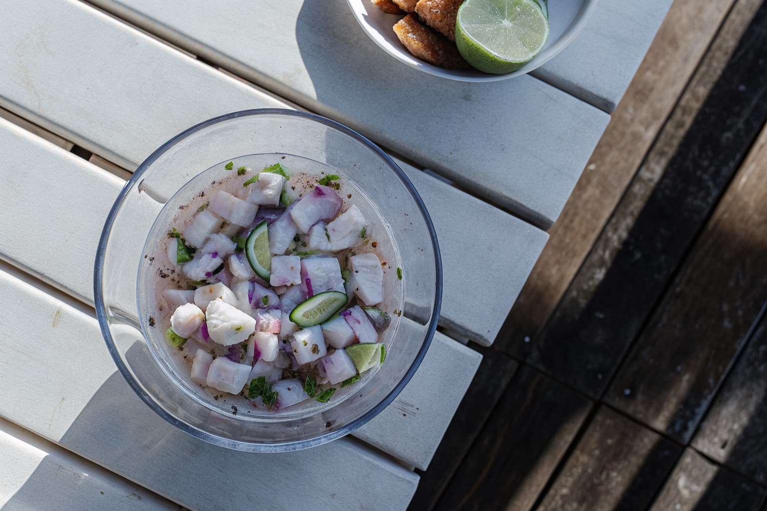 Fresh corvina ceviche in a glass bowl with lime and cilantro on a wooden table in Jaco Costa Rica